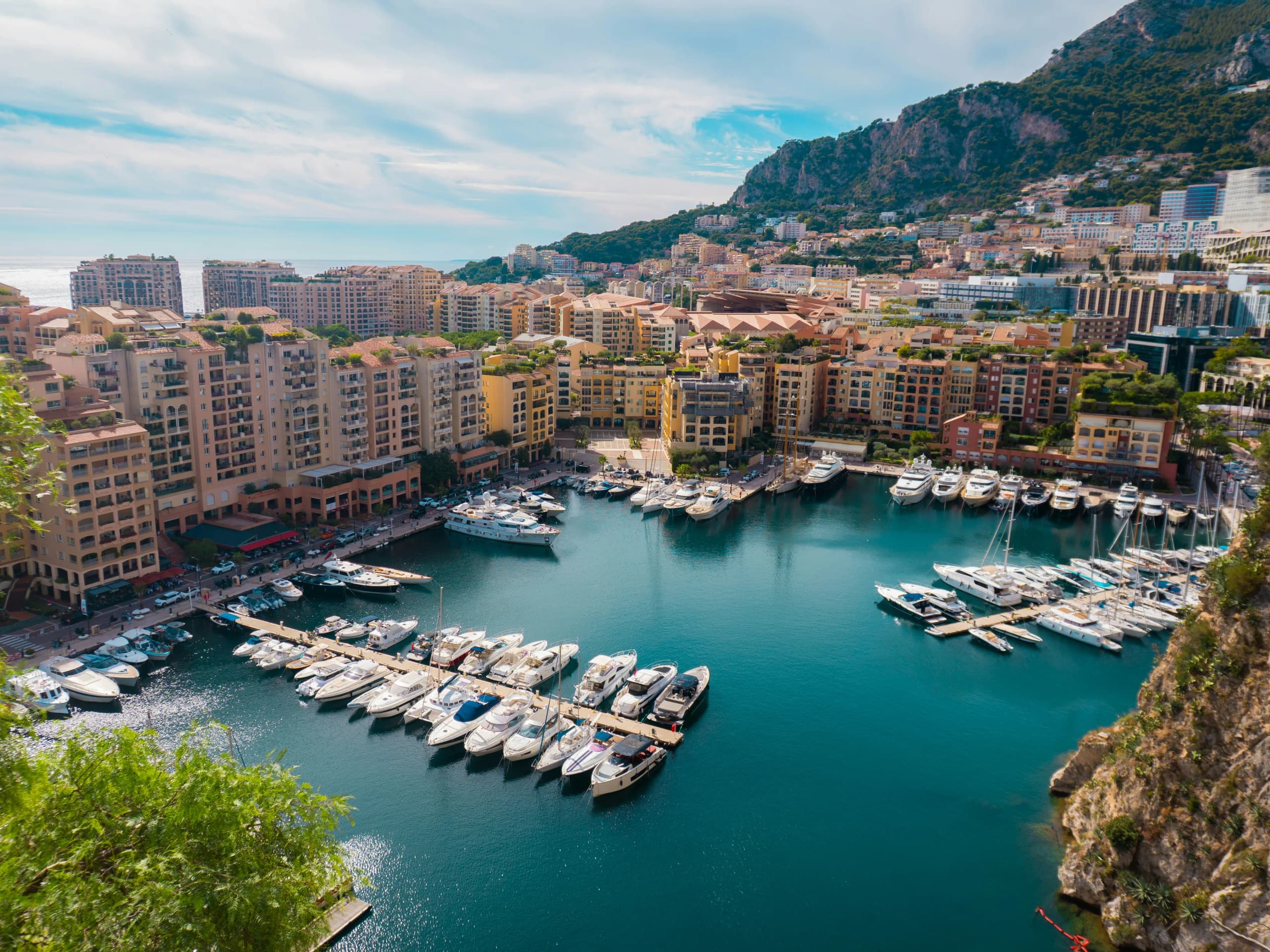The marina at Fontvieille, yachts moored below the pastel terraces behind.