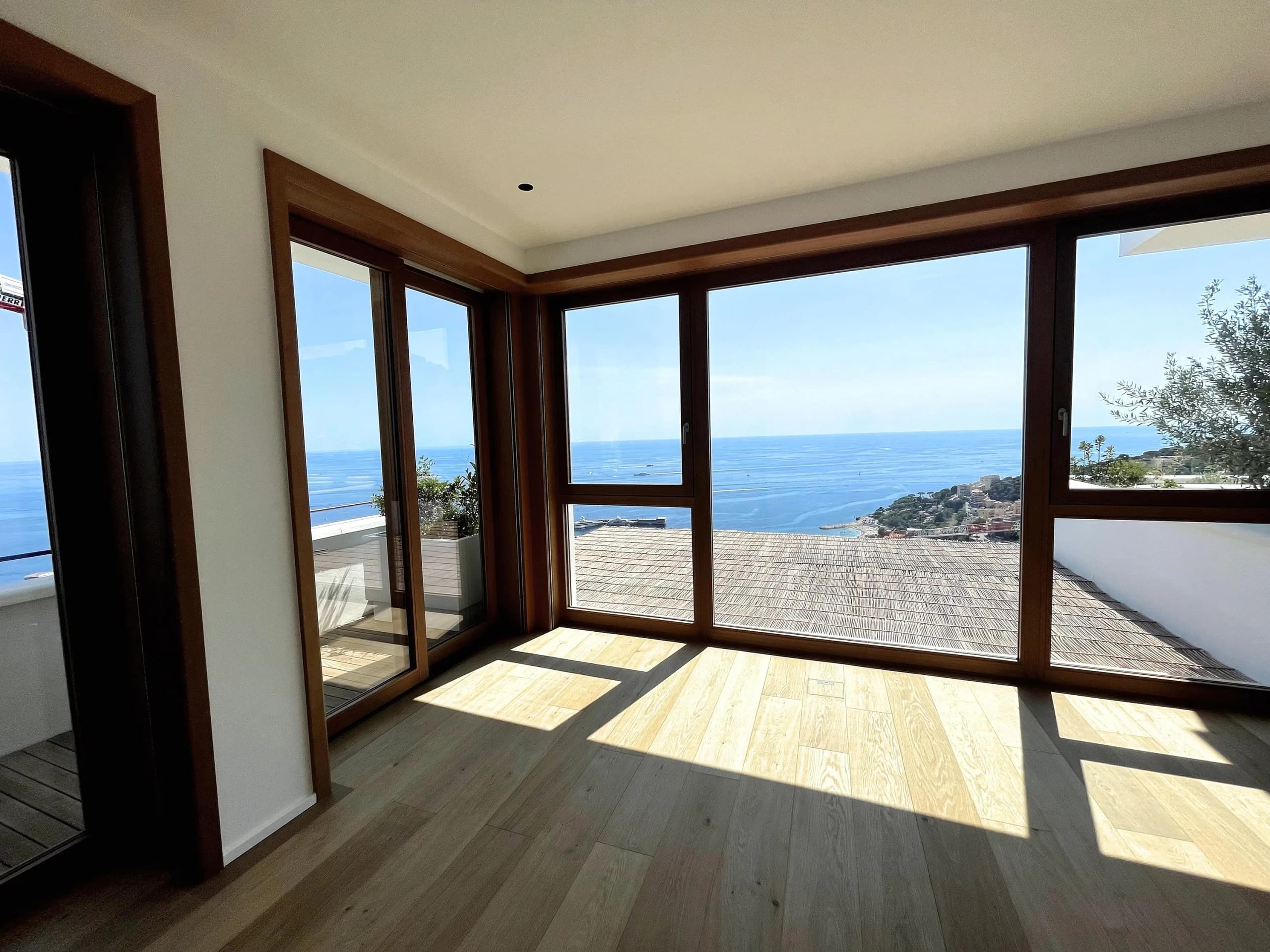 An empty Monaco apartment with the floor bare and the sea through full-height windows.