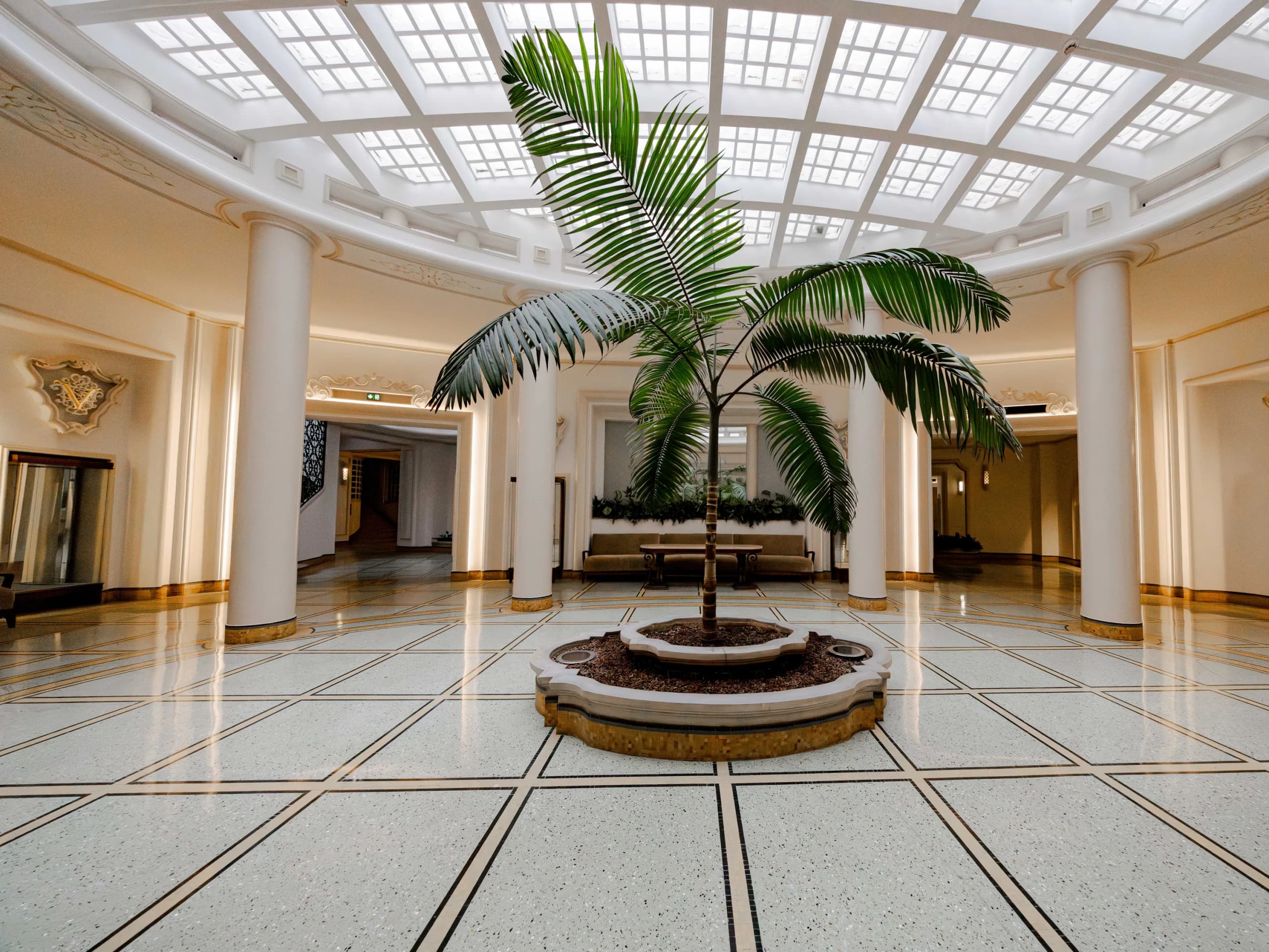 The lobby of a Monaco apartment building, daylight falling through a glazed roof onto a terrazzo floor.